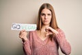 Young beautiful redhead woman asking for veggie food holding paper with vegan message with angry face, negative sign showing