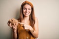 Young beautiful redhead woman holding bowl of healthy cornflakes cereals very happy pointing with hand and finger