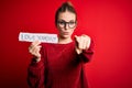 Young beautiful redhead woman holding paper with love yourself message pointing with finger to the camera and to you, hand sign, Royalty Free Stock Photo