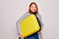Young beautiful redhead woman holding suitcase prepared to business travel with a happy face standing and smiling with a confident Royalty Free Stock Photo