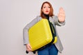 Young beautiful redhead woman holding suitcase prepared to business travel with open hand doing stop sign with serious and Royalty Free Stock Photo