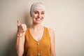 Young beautiful redhead woman injured for accident wearing bandage on head doing happy thumbs up gesture with hand