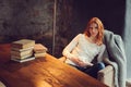 Young beautiful redhead woman relaxing at home in the autumn cozy evening and reading book