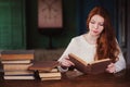 Young beautiful redhead woman relaxing at home in the autumn cozy evening and reading book Royalty Free Stock Photo