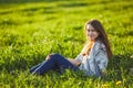 Young beautiful redhead woman sits on a green meadow, looking at camera Royalty Free Stock Photo