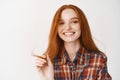 Young beautiful redhead woman smiling with white perfect teeth at camera, touching ginger hair strand and looking happy Royalty Free Stock Photo