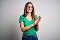 Young beautiful redhead woman wearing casual green t-shirt and glasses over white background clapping and applauding happy and Royalty Free Stock Photo