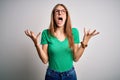 Young beautiful redhead woman wearing casual green t-shirt and glasses over white background crazy and mad shouting and yelling Royalty Free Stock Photo