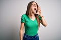 Young beautiful redhead woman wearing casual green t-shirt and glasses over white background shouting and screaming loud to side Royalty Free Stock Photo