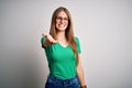 Young beautiful redhead woman wearing casual green t-shirt and glasses over white background smiling cheerful offering palm hand Royalty Free Stock Photo