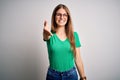 Young beautiful redhead woman wearing casual green t-shirt and glasses over white background smiling friendly offering handshake Royalty Free Stock Photo