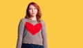 Young beautiful redhead woman wearing casual heart sweater with serious expression on face