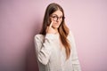 Young beautiful redhead woman wearing casual sweater and glasses over pink background Pointing to the eye watching you gesture, Royalty Free Stock Photo