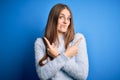Young beautiful redhead woman wearing casual sweater over isolated blue background Pointing to both sides with fingers, different Royalty Free Stock Photo