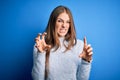 Young beautiful redhead woman wearing casual sweater over isolated blue background smiling funny doing claw gesture as cat, Royalty Free Stock Photo