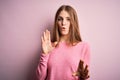 Young beautiful redhead woman wearing casual sweater over isolated pink background Moving away hands palms showing refusal and Royalty Free Stock Photo