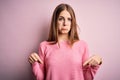 Young beautiful redhead woman wearing casual sweater over isolated pink background Pointing down looking sad and upset, indicating Royalty Free Stock Photo