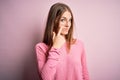 Young beautiful redhead woman wearing casual sweater over isolated pink background Pointing to the eye watching you gesture, Royalty Free Stock Photo