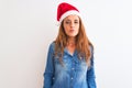 Young beautiful redhead woman wearing christmas hat over isolated background looking at the camera blowing a kiss on air being Royalty Free Stock Photo