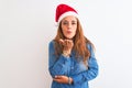 Young beautiful redhead woman wearing christmas hat over isolated background looking at the camera blowing a kiss with hand on air Royalty Free Stock Photo