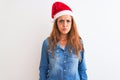 Young beautiful redhead woman wearing christmas hat over isolated background puffing cheeks with funny face Royalty Free Stock Photo