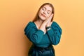 Young beautiful redhead woman wearing elegant and sexy look sleeping tired dreaming and posing with hands together while smiling Royalty Free Stock Photo