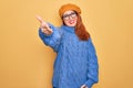 Young beautiful redhead woman wearing french beret and glasses over yellow background smiling friendly offering handshake as Royalty Free Stock Photo