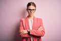 Young beautiful redhead woman wearing jacket and glasses over isolated pink background skeptic and nervous, disapproving Royalty Free Stock Photo