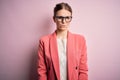 Young beautiful redhead woman wearing jacket and glasses over isolated pink background skeptic and nervous, frowning upset because Royalty Free Stock Photo