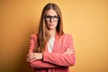 Young beautiful redhead woman wearing jacket and glasses over isolated yellow background skeptic and nervous, disapproving Royalty Free Stock Photo