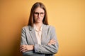 Young beautiful redhead woman wearing jacket and glasses over isolated yellow background skeptic and nervous, disapproving Royalty Free Stock Photo