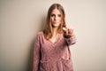 Young beautiful redhead woman wearing pink casual sweater over isolated white background Pointing with finger up and angry Royalty Free Stock Photo