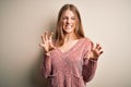 Young beautiful redhead woman wearing pink casual sweater over isolated white background smiling funny doing claw gesture as cat, Royalty Free Stock Photo