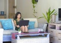 Young beautiful and relaxed Asian Chinese woman on her 20s or 30s sitting happy at living room home sofa couch working or using co Royalty Free Stock Photo