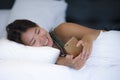 Young beautiful and relaxed Asian Chinese woman smiling happy lying on bed at home bedroom using internet on mobile phone Royalty Free Stock Photo