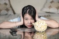 Young beautiful and relaxed Asian Chinese woman watching Korean drama on television on sad romantic movie eating popcorn at home Royalty Free Stock Photo