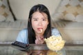 Young beautiful and relaxed Asian Japanese woman watching Korean drama on television on sad romantic movie eating popcorn at home Royalty Free Stock Photo