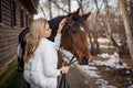 Young beautiful rider woman blonde with long hair in white clothes standing near horse Royalty Free Stock Photo