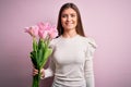 Young beautiful romantic woman with blue eyes holding beauty bouquet of pink tulips with a happy face standing and smiling with a Royalty Free Stock Photo