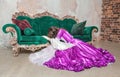 Young beautiful sad crying woman in fantasy rococo style medieval dress sitting on the floor near sofa Royalty Free Stock Photo