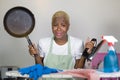 Young beautiful sad and depressed afro American black woman with cooking pan and iron working stressed and tired at home kitchen o