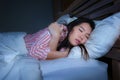 Young beautiful sad and depressed Asian Chinese woman trembling in bed suffering cold and flu at night feeling unwell at nigh in