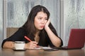 Young beautiful sad and depressed Asian Korean businesswoman working exhausted and frustrated at office computer desk with rain on