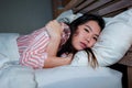 Young beautiful sad and depressed Asian Korean woman trembling in bed suffering cold and flu at night feeling unwell at nigh in Royalty Free Stock Photo