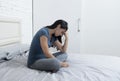 Beautiful sad and depressed Latin woman sitting on bed at home f Royalty Free Stock Photo