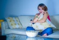 Young beautiful sad latin woman watching drama romantic movie eating popcorn sitting at home sofa couch late night in sadness face Royalty Free Stock Photo