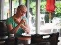 Young beautiful sad woman eating melted ice cream on the terrace of a street cafe. Royalty Free Stock Photo