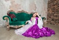 Young beautiful sad woman in fantasy rococo style medieval dress sitting on the floor near sofa Royalty Free Stock Photo