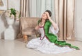 Young beautiful sad woman in green rococo style medieval dress sitting on the floor Royalty Free Stock Photo
