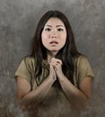Young beautiful sad and worried Asian Korean woman in praying hands gesture looking stressed and desperate suffering pain and expe Royalty Free Stock Photo